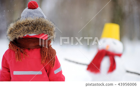 Little boy having fun with snowman in snowy park Little boy having fun with snowman in snowy park 43956006