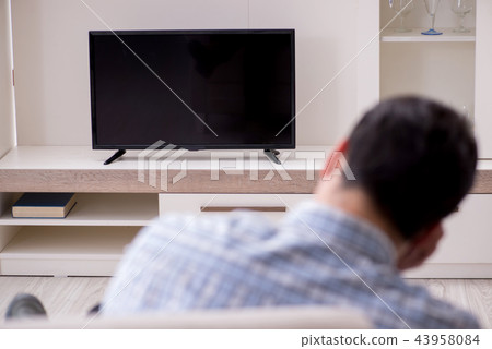 Young man watching tv at home Young man watching tv at home 43958084
