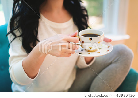 Young woman holding a cup of coffee Young woman holding a cup of coffee 43959430