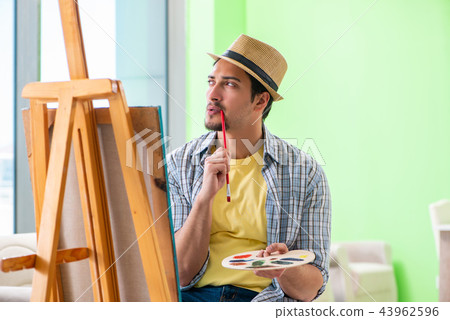 Young male artist working on new painting in his studio Young male artist working on new painting in his studio 43962596