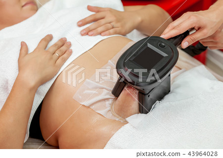 Woman getting cryolipolysis in cosmetic cabinet 43964028