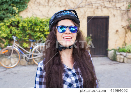 Happy woman with helmet and sunglasses posing backgound bicycle and street 43964092