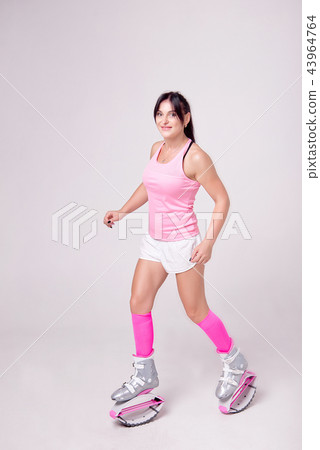 Beautiful athletic woman wearing in sports style clothing with kangoo jumps boots on her legs makes 43964764