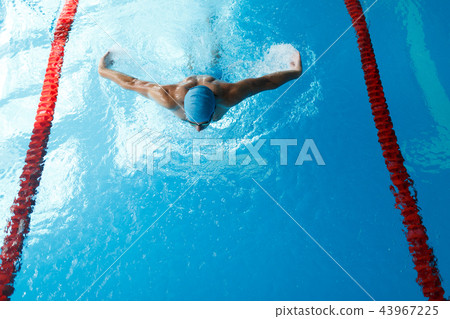 Photo of sports man in blue cap swimming on path in pool 43967225