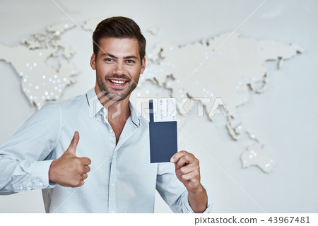 Happy young man with passports and tickets in the office of travel company Happy young man with passports and tickets in the office of travel company 43967481