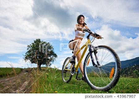 Young happy woman riding bicycle in the mountains at summer day 43967907