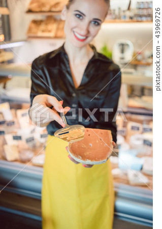 Beautiful woman offering cheese on delicatessen counter Beautiful woman offering cheese on delicatessen counter 43969726