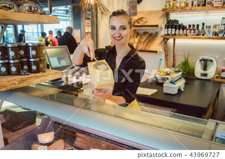 Customer trying bit of cheese at the deli counter Customer trying bit of cheese at the deli counter 43969727