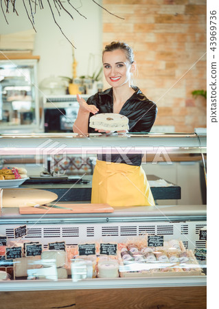 Salesgirl selling cheese in deli or supermarket Salesgirl selling cheese in deli or supermarket 43969736