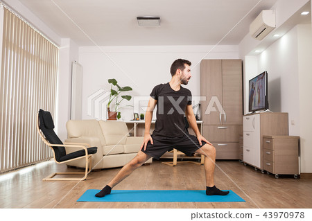 Bearded man doing Warrior II yoga posing and stretching his muscles Bearded man doing Warrior II yoga posing and stretching his muscles 43970978