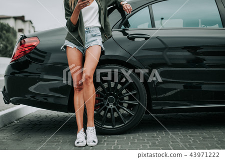 Lady sending message on phone near vehicle Lady sending message on phone near vehicle 43971222