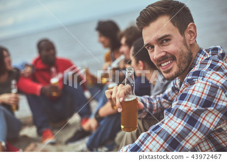 Happy man sitting near his friends at the seaside 43972467