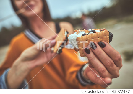 Pretty woman holding biscuit in her hand with her colleague Pretty woman holding biscuit in her hand with her colleague 43972487