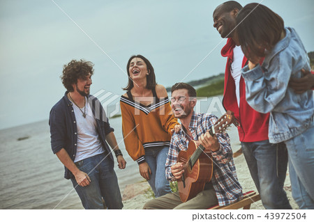 Group of happy friends are singing on seaside Group of happy friends are singing on seaside 43972504