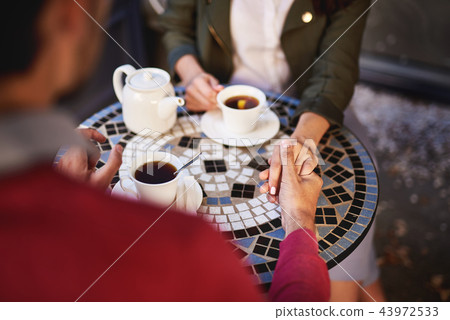 Lovely couple holding hands while spending time in outdoor cafe 43972533