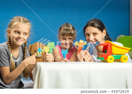 Mom with two daughters playing in a makeshift finger puppet theater 43972629