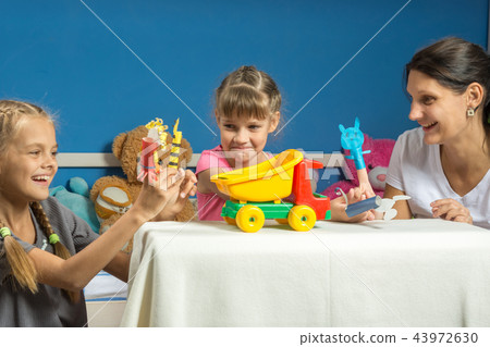 Mom plays with two daughters in a self-made finger puppet theater 43972630