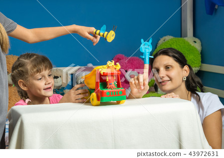 An enthusiastic mother plays with daughters in a self-made finger puppet theater 43972631