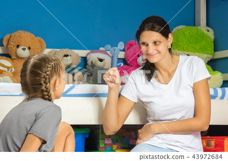 Mom shows her daughter a homemade figurine Mom shows her daughter a homemade figurine 43972684