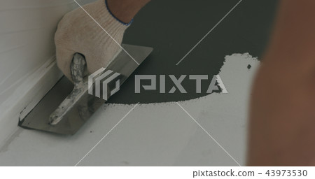 closeup male worker applying micro concrete plaster coating on the floor with a trowel 43973530