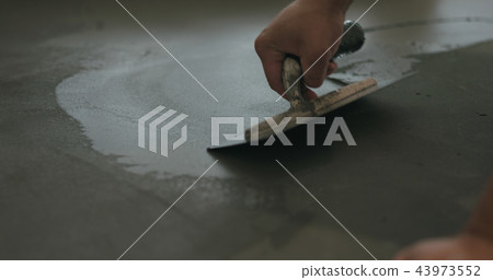 closeup worker applying micro concrete on the floor with a trowel 43973552