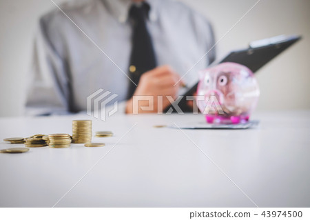 Businessman putting coins into piggy bank, writing to report and Businessman putting coins into piggy bank, writing to report and 43974500