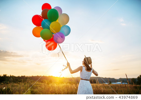 Girl with colorful balloons walking in wheat field Girl with colorful balloons walking in wheat field 43974869