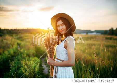 Woman holds wheat bouquet in the field at sunset Woman holds wheat bouquet in the field at sunset 43974872