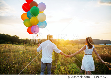Couple holds balloons and kissing in wheat field Couple holds balloons and kissing in wheat field 43974879
