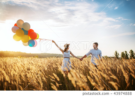 Husband and wife walks with bunch of balloons 43974888
