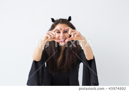 Halloween and masquerade concept - Beautiful young woman posing in light background 43974892