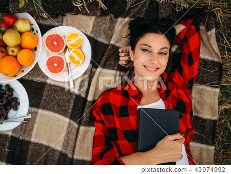 Woman lies on plaid, top view, picnic in field Woman lies on plaid, top view, picnic in field 43974992