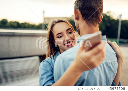 Couple hugs and using gadgets, modern relationship Couple hugs and using gadgets, modern relationship 43975506