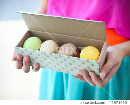 Girl holding colorful French macaroons in hands Girl holding colorful French macaroons in hands 43975619