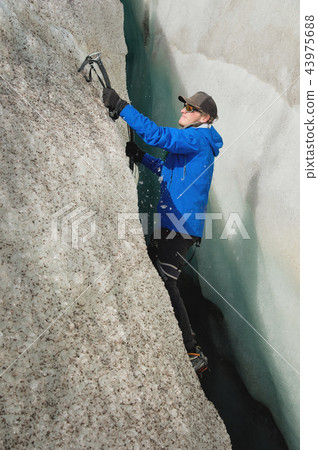 A free climber without insurance with two ice axes rises from a crack in the glacier. Free climbing 43975688