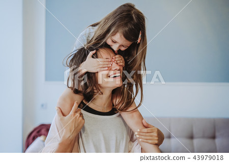 beautiful little daughter piggybacking on her happy mother beautiful little daughter piggybacking on her happy mother 43979018