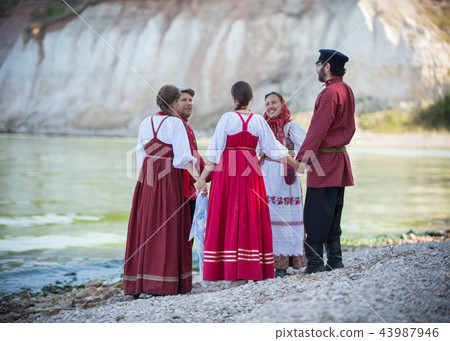 A group of people in Russian folk costumes dancing in a beautiful landscape, in the foreground is 43987946