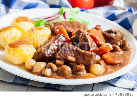 Beef Bourguignon stew served with baked potatoes Beef Bourguignon stew served with baked potatoes 43989083