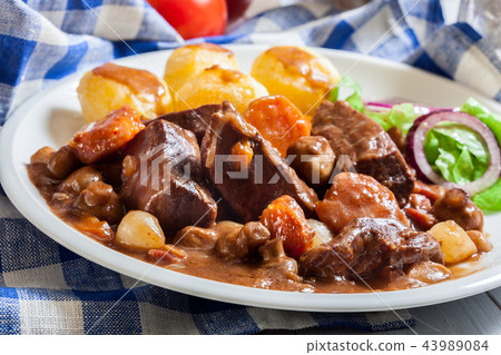 Beef Bourguignon stew served with baked potatoes Beef Bourguignon stew served with baked potatoes 43989084