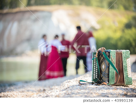 Shot of the accordion, on the background of a group of young people in Russian national costumes 43993139