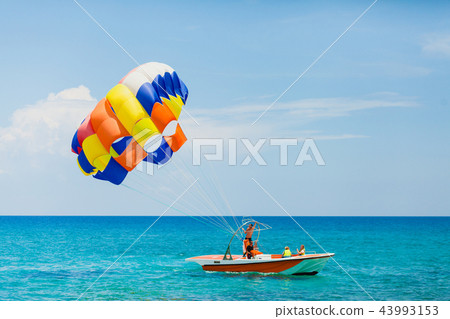 Couple of tourists flying on a colorful parachute 43993153