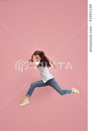 Freedom in moving. Pretty young woman jumping against pink background Freedom in moving. Pretty young woman jumping against pink background 43993199