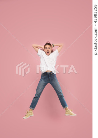 Freedom in moving. Pretty young woman jumping against pink background Freedom in moving. Pretty young woman jumping against pink background 43993259