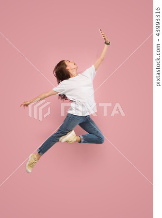 Full length of pretty young woman with mobile phone while jumping 43993316