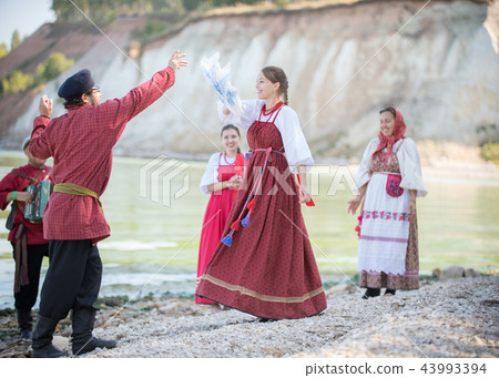 Young people in Russian national costumes dancing folk dances, playing accordion Young people in Russian national costumes dancing folk dances, playing accordion 43993394