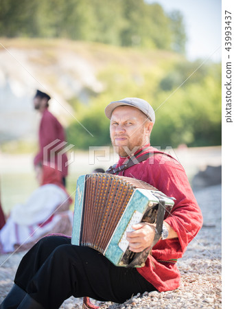 A man in Russian national costume stand on the background of an amazing landscape playing accordion 43993437