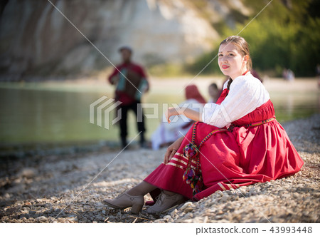 A girl in Russian national costume sitting on a sand on the background of an amazing landscape 43993448