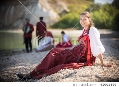 A beautiful girl in red Russian national costume pose for the camera on the background of an amazing A beautiful girl in red Russian national costume pose for the camera on the background of an amazing 43993455