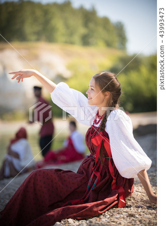 A girl in Russian national costume pose for the camera on the background of an amazing landscape A girl in Russian national costume pose for the camera on the background of an amazing landscape 43993473