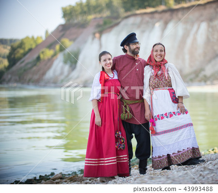 A man and two women in Russian national costumes pose for the camera on the background of an amazing A man and two women in Russian national costumes pose for the camera on the background of an amazing 43993488
